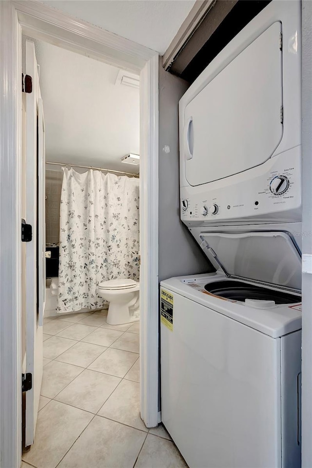 laundry room with light tile patterned floors and stacked washer / dryer