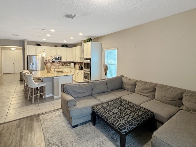 living room featuring a textured ceiling, light wood-type flooring, and sink