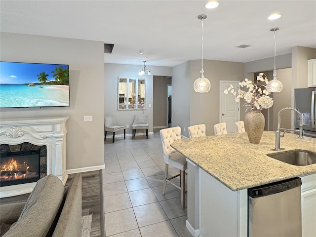 kitchen with a kitchen breakfast bar, stainless steel appliances, sink, white cabinets, and hanging light fixtures