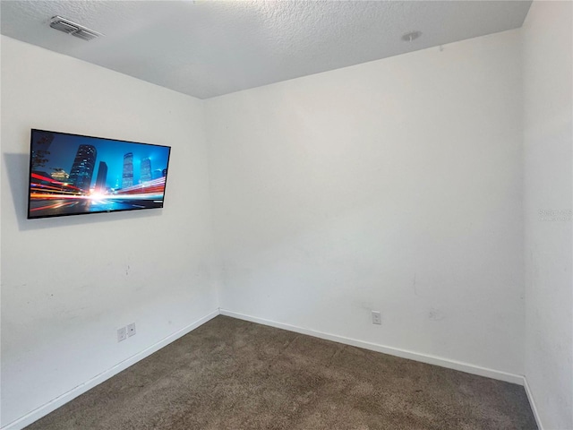 empty room featuring dark colored carpet and a textured ceiling