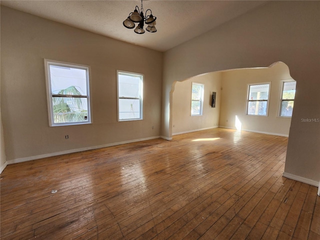 unfurnished living room featuring a chandelier, a healthy amount of sunlight, and hardwood / wood-style flooring