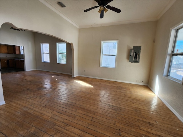 unfurnished living room featuring electric panel, dark hardwood / wood-style floors, ceiling fan, and ornamental molding