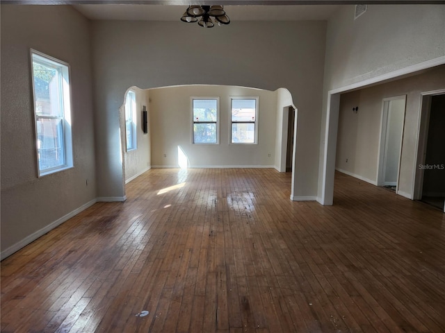 unfurnished living room featuring a chandelier, a towering ceiling, and dark wood-type flooring