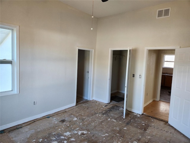 unfurnished bedroom with a towering ceiling, a walk in closet, and a closet