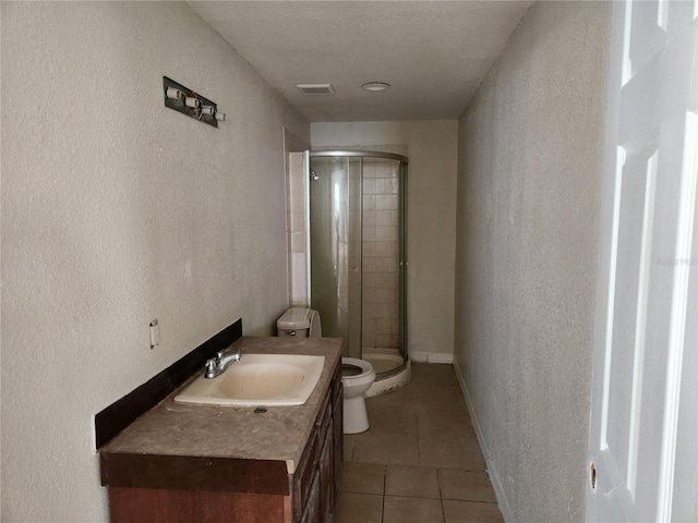 bathroom featuring toilet, vanity, tile patterned floors, and an enclosed shower