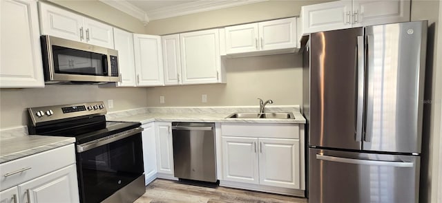 kitchen featuring sink, light hardwood / wood-style flooring, crown molding, white cabinets, and appliances with stainless steel finishes