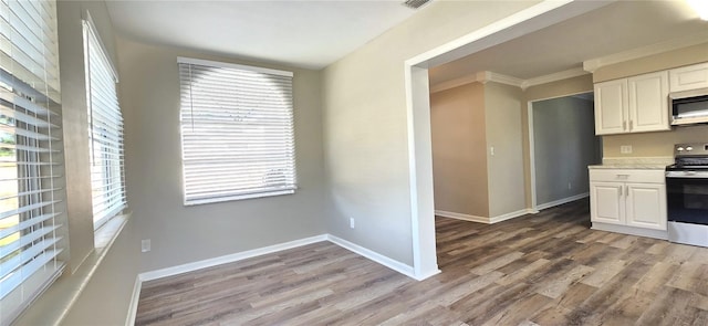 kitchen with light wood-type flooring, stainless steel appliances, white cabinetry, and plenty of natural light