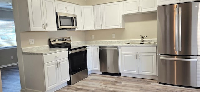 kitchen featuring white cabinetry, sink, stainless steel appliances, and light hardwood / wood-style floors