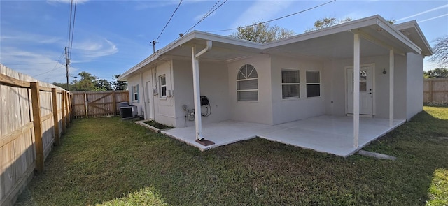 back of property with cooling unit, a patio area, and a lawn