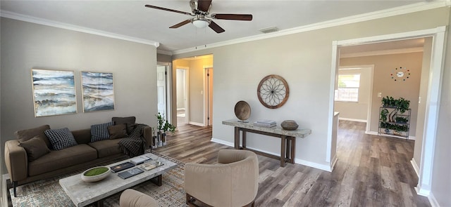 living room featuring ceiling fan, wood finished floors, visible vents, baseboards, and ornamental molding