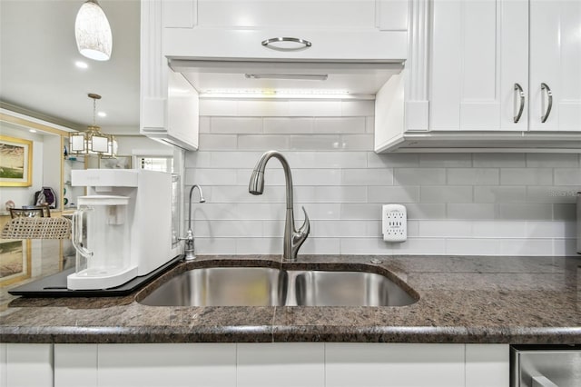 kitchen with dark stone countertops, a sink, white cabinetry, and decorative backsplash