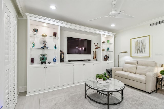 living room featuring ceiling fan, light wood-style floors, visible vents, and crown molding