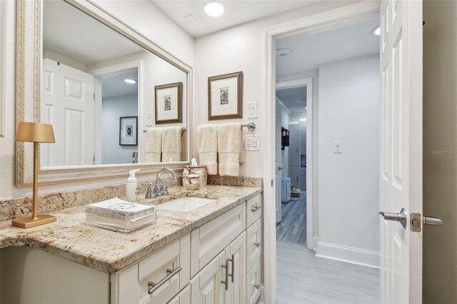 bathroom with baseboards, wood finished floors, and vanity