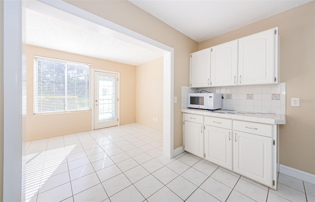 kitchen with backsplash, white cabinetry, and light tile patterned flooring