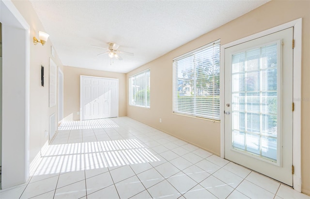 unfurnished room featuring light tile patterned floors, a textured ceiling, and ceiling fan