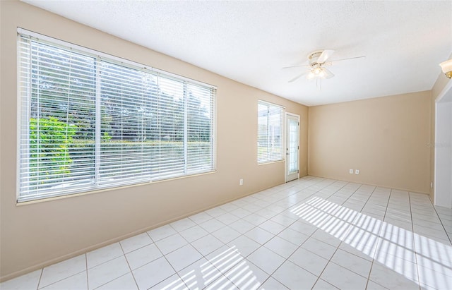 tiled spare room featuring a textured ceiling and ceiling fan