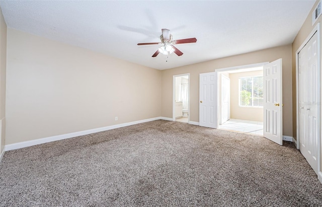 unfurnished bedroom with carpet flooring, ceiling fan, ensuite bathroom, and a closet