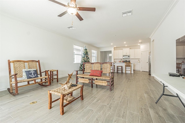 living room featuring ornamental molding, ceiling fan, and light hardwood / wood-style flooring