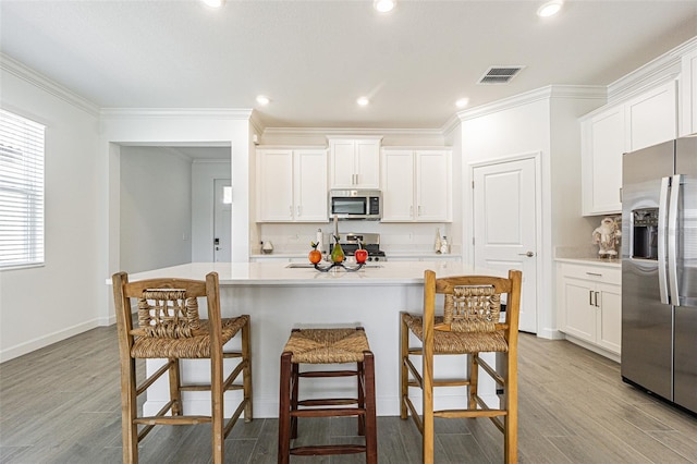 kitchen with a center island with sink, white cabinets, and appliances with stainless steel finishes