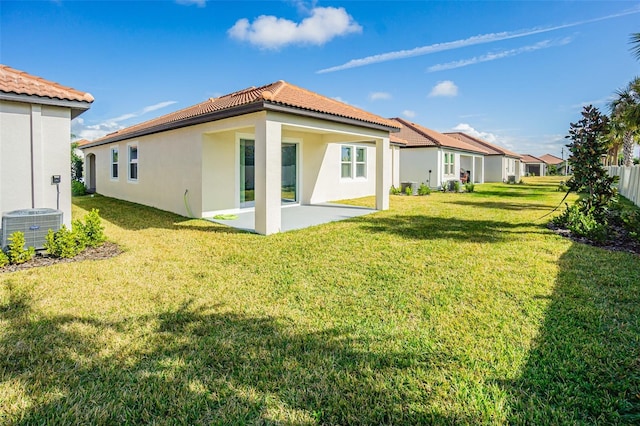 back of house with cooling unit, a lawn, and a patio