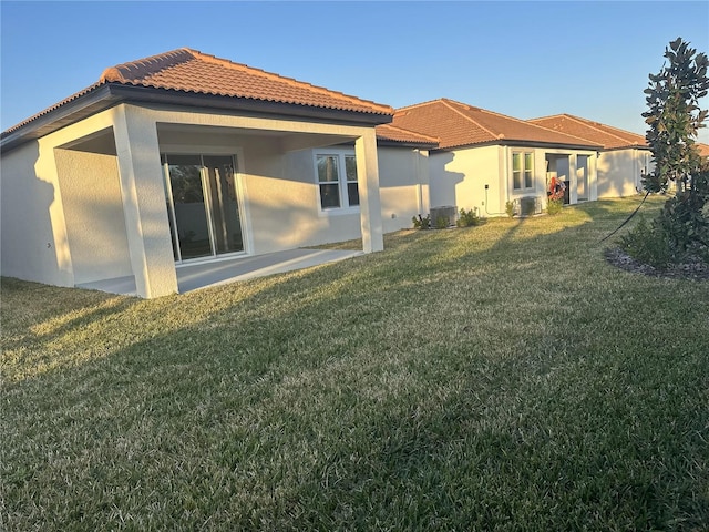 rear view of house featuring central AC unit and a lawn