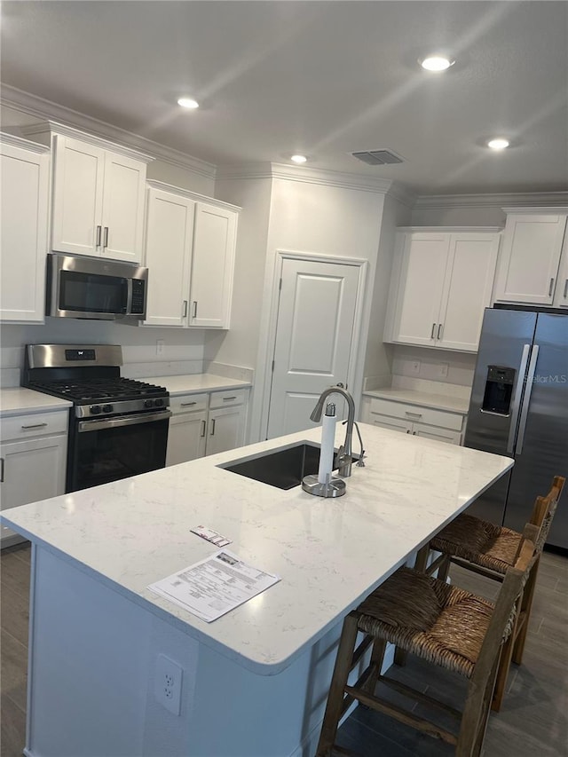 kitchen featuring appliances with stainless steel finishes, an island with sink, a breakfast bar area, and white cabinets