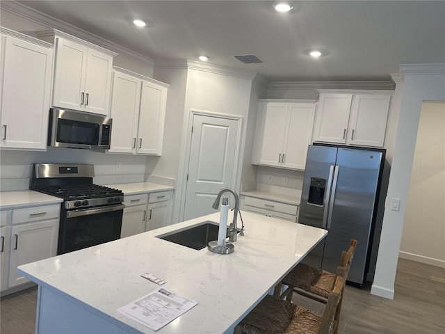 kitchen with stainless steel appliances, sink, a center island with sink, and white cabinets