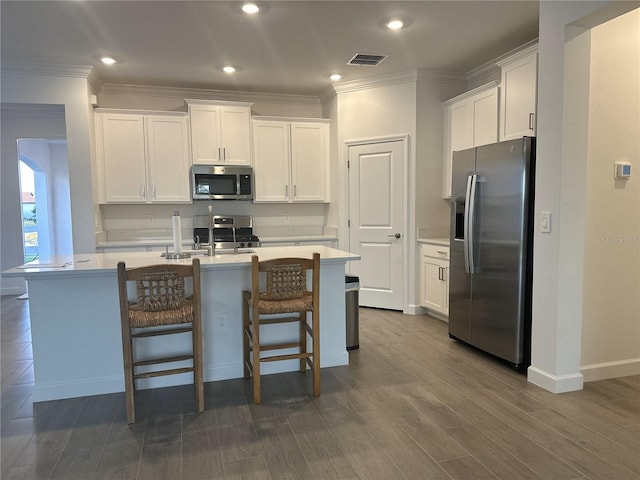 kitchen with stainless steel appliances, white cabinetry, a breakfast bar, and a center island with sink