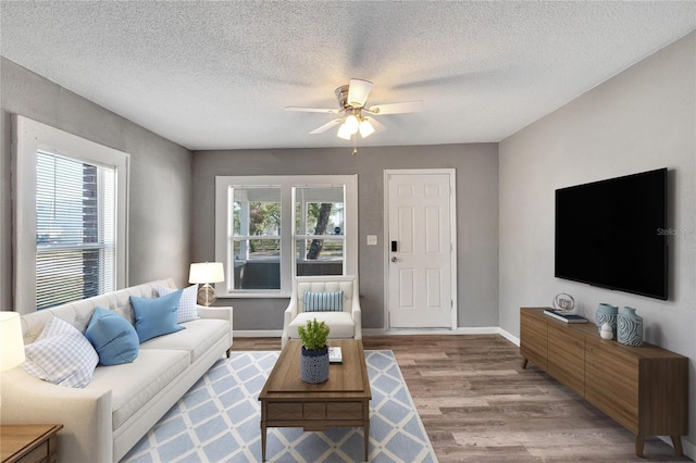 living room featuring a textured ceiling, light hardwood / wood-style flooring, a wealth of natural light, and ceiling fan