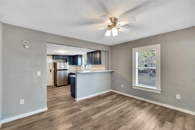 kitchen with kitchen peninsula, stainless steel fridge, blue cabinetry, and hardwood / wood-style floors