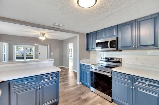 kitchen featuring blue cabinetry, ceiling fan, a textured ceiling, and appliances with stainless steel finishes