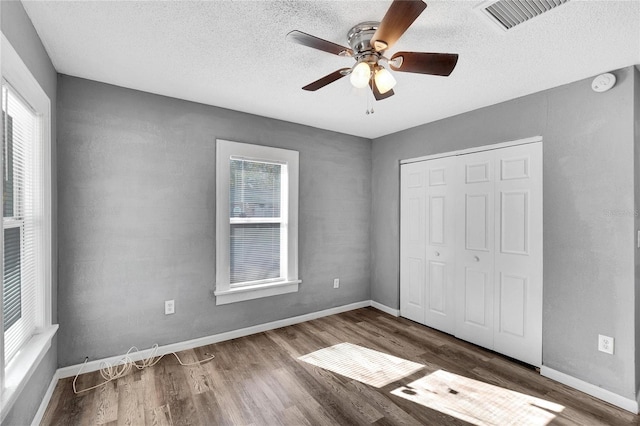 unfurnished bedroom featuring ceiling fan, dark hardwood / wood-style floors, a textured ceiling, and a closet