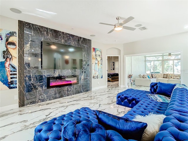 living room featuring ceiling fan, a premium fireplace, and tile walls