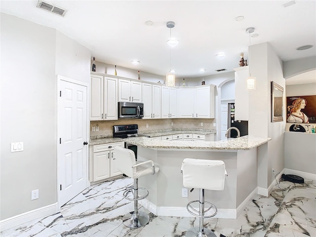 kitchen with white cabinetry, light stone countertops, kitchen peninsula, stove, and a breakfast bar