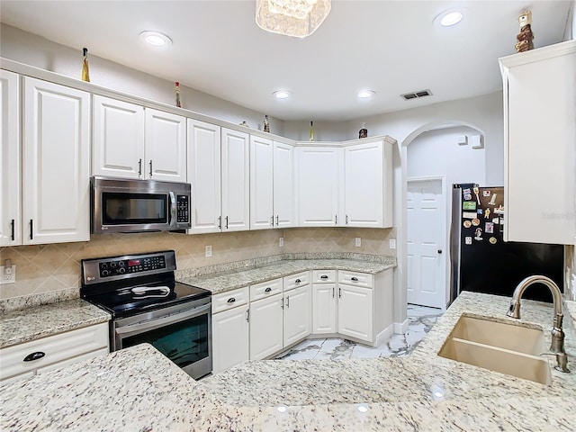 kitchen featuring white cabinets, decorative backsplash, stainless steel appliances, and sink