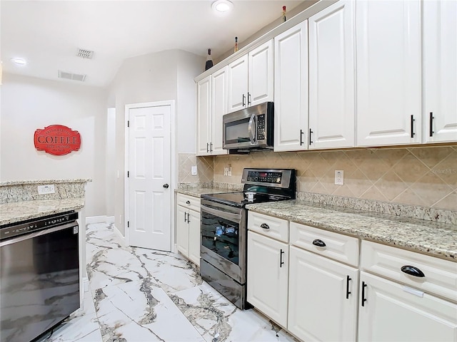 kitchen with backsplash, white cabinetry, stainless steel appliances, and light stone counters