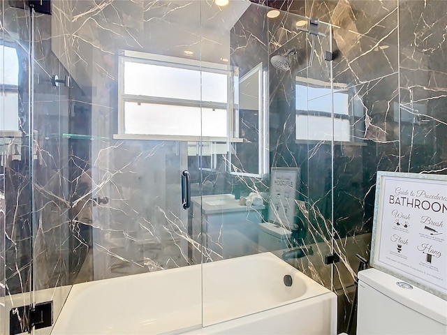 bathroom with toilet, combined bath / shower with glass door, and tile walls