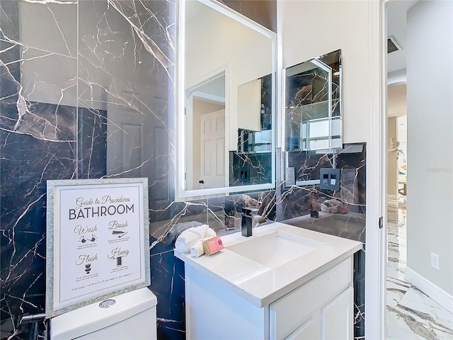 bathroom featuring vanity, tile walls, and toilet