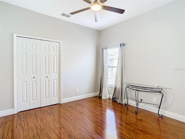 unfurnished bedroom featuring hardwood / wood-style flooring, ceiling fan, and a closet