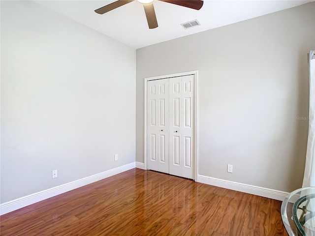 unfurnished bedroom featuring ceiling fan, a closet, and hardwood / wood-style flooring