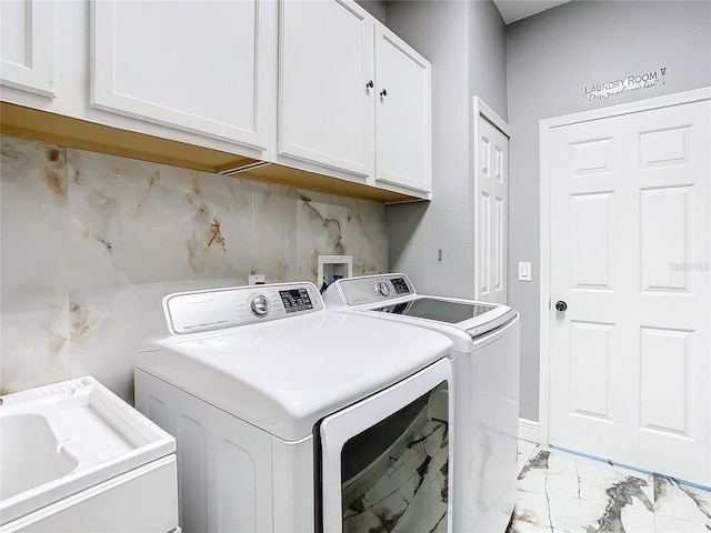 clothes washing area with cabinets, washing machine and dryer, and sink