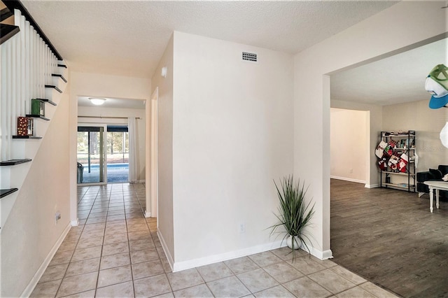 corridor featuring a textured ceiling and light hardwood / wood-style floors