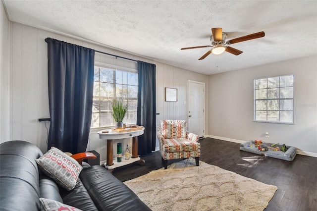 living room featuring ceiling fan, dark wood-type flooring, and a textured ceiling