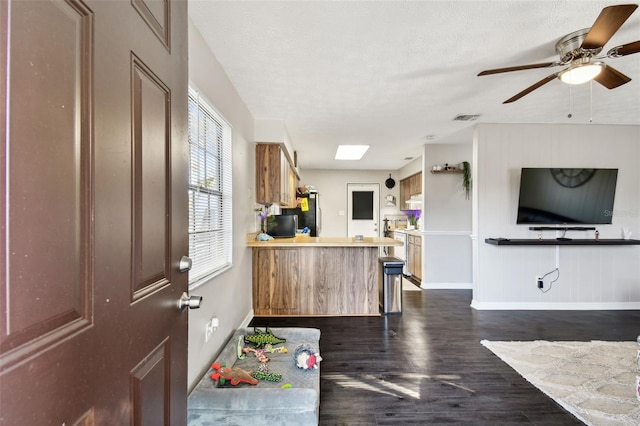 interior space featuring ceiling fan, dark hardwood / wood-style flooring, a textured ceiling, and a skylight