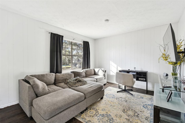 living room with dark hardwood / wood-style flooring, a textured ceiling, and wooden walls