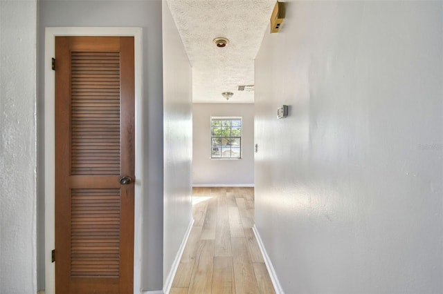 hall featuring a textured ceiling and light wood-type flooring