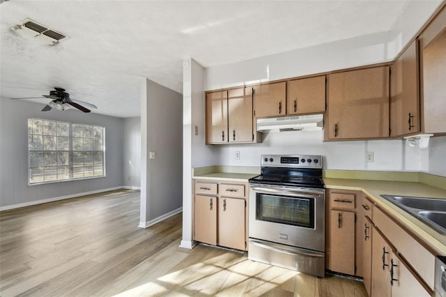 kitchen with stainless steel electric stove, sink, ceiling fan, light wood-type flooring, and a textured ceiling