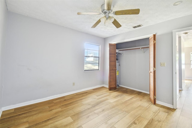 unfurnished bedroom with ceiling fan, a closet, light hardwood / wood-style floors, and a textured ceiling