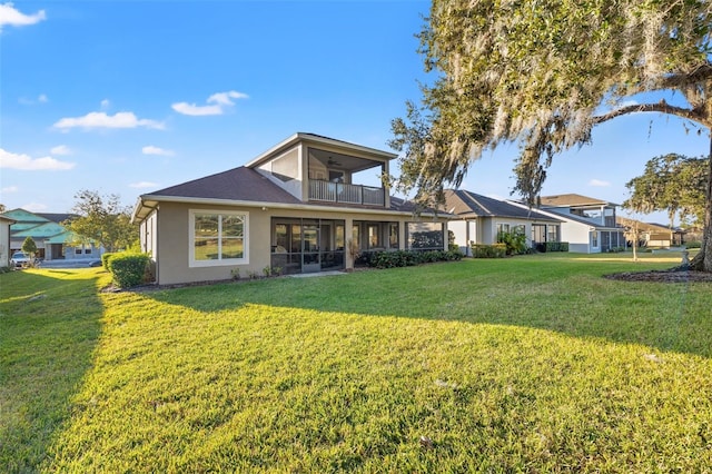 back of property with a yard and a balcony