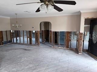 spare room featuring ceiling fan with notable chandelier and crown molding